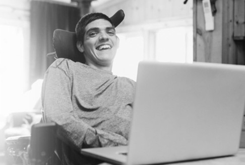 Man in wheelchair smiling at computer